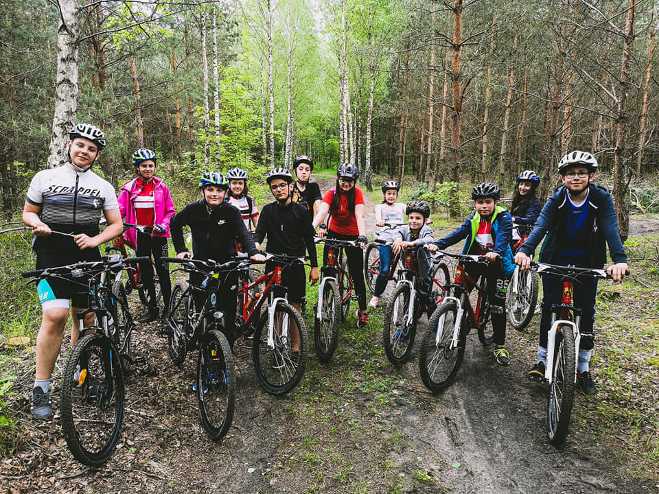 Uczniowie na rowerach podczas zajęć sportowych w lesie