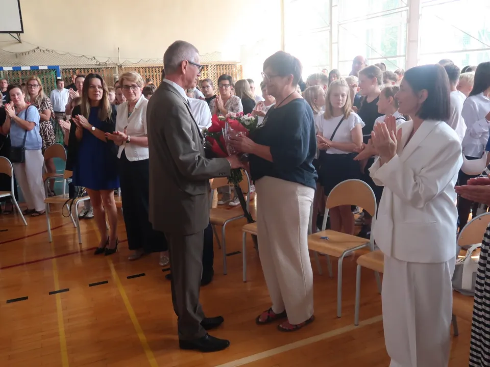 Przedstawiciele szkoły podczas rozpoczęcia roku szkolnego na sali gimnastycznej.