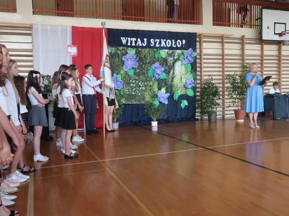 Uczniowie uczestniczący w uroczystości na sali gimnastycznej.