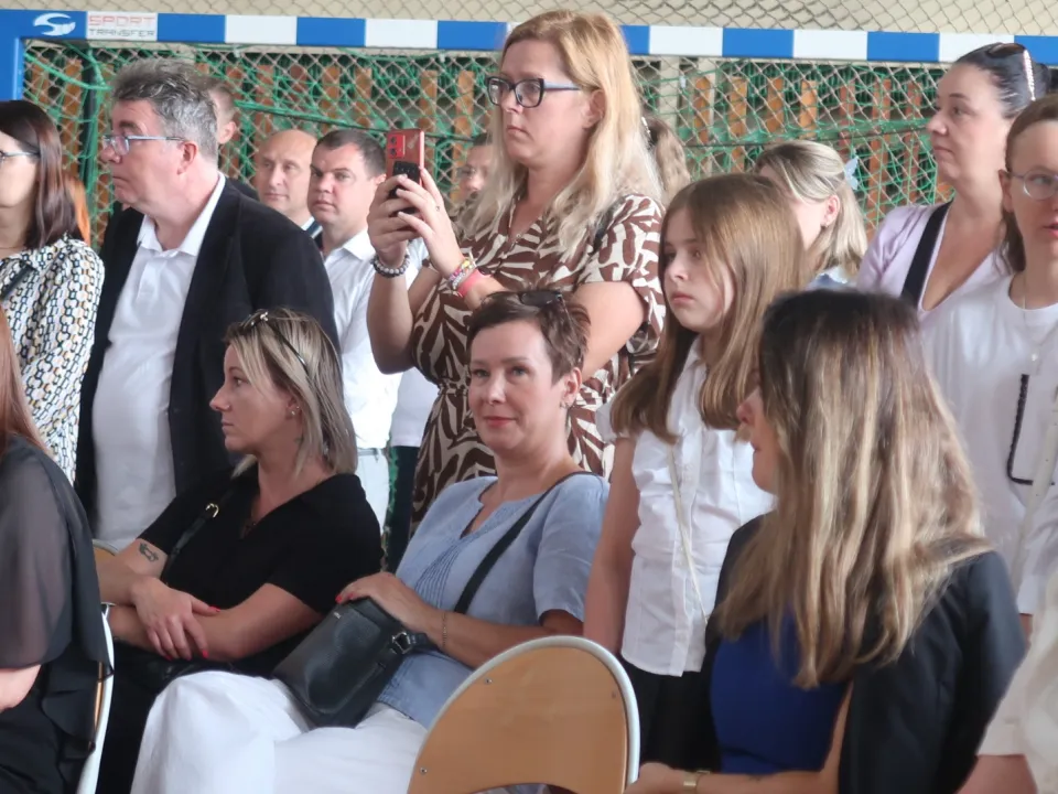 Uczniowie i nauczyciele obserwujący uroczystość.